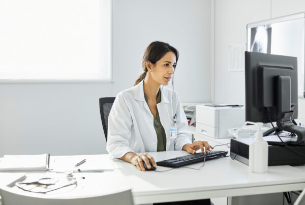 Women in a white coat looking at a computer