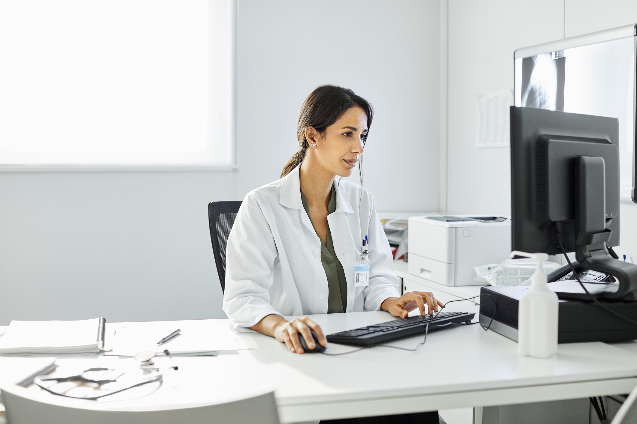 Women in a white coat looking at a computer