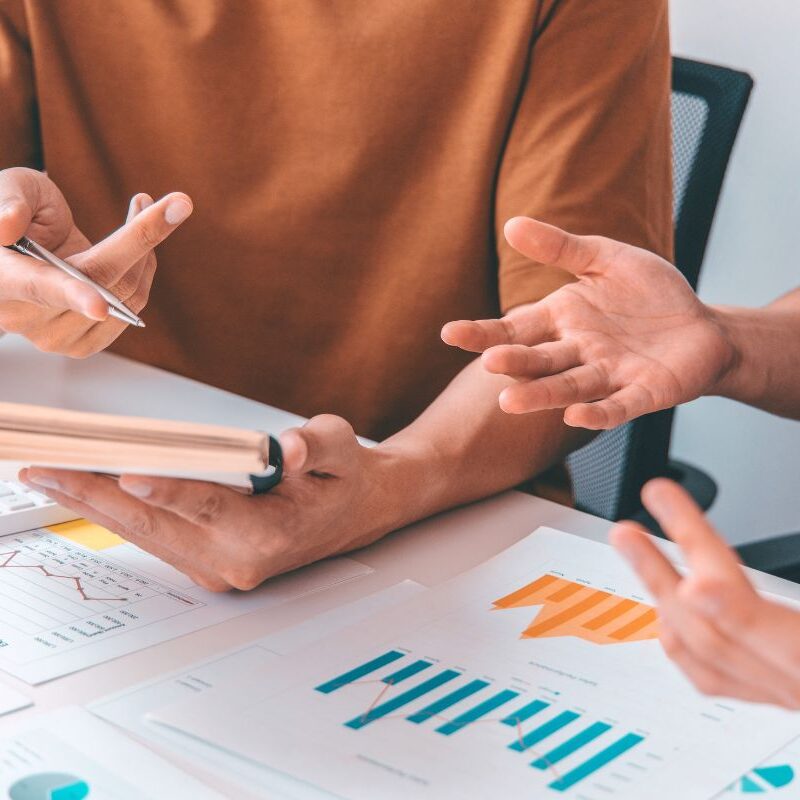 2 people working together looking at graphs and taking notes