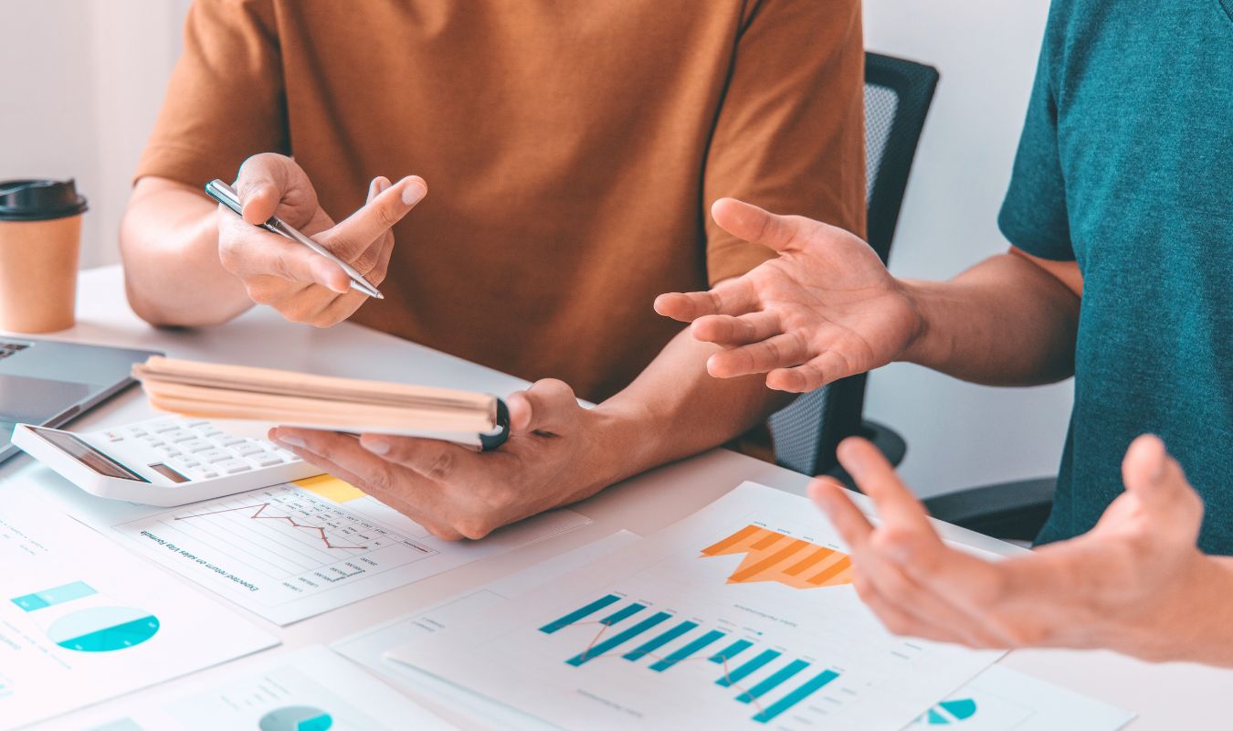 2 people working together looking at graphs and taking notes