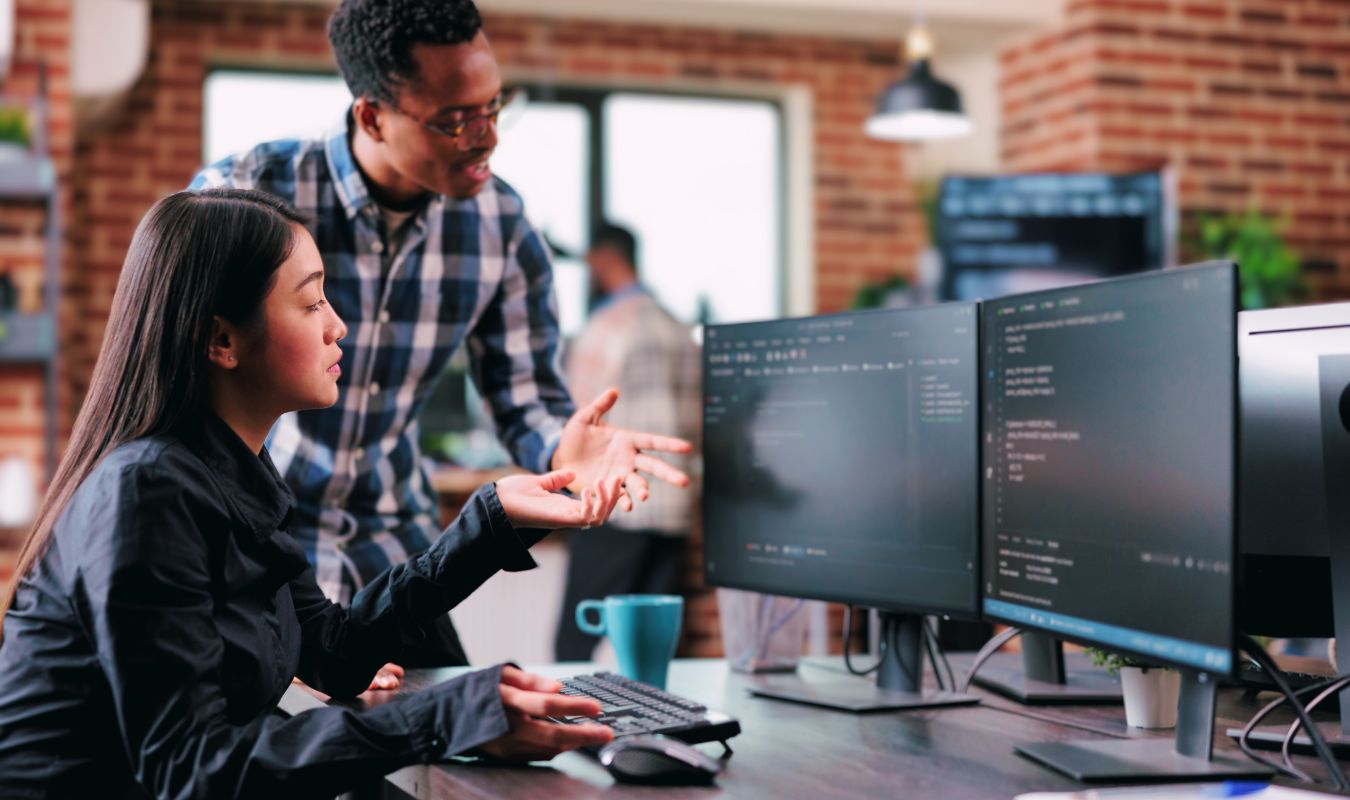 2 people looking at a computer discussing code